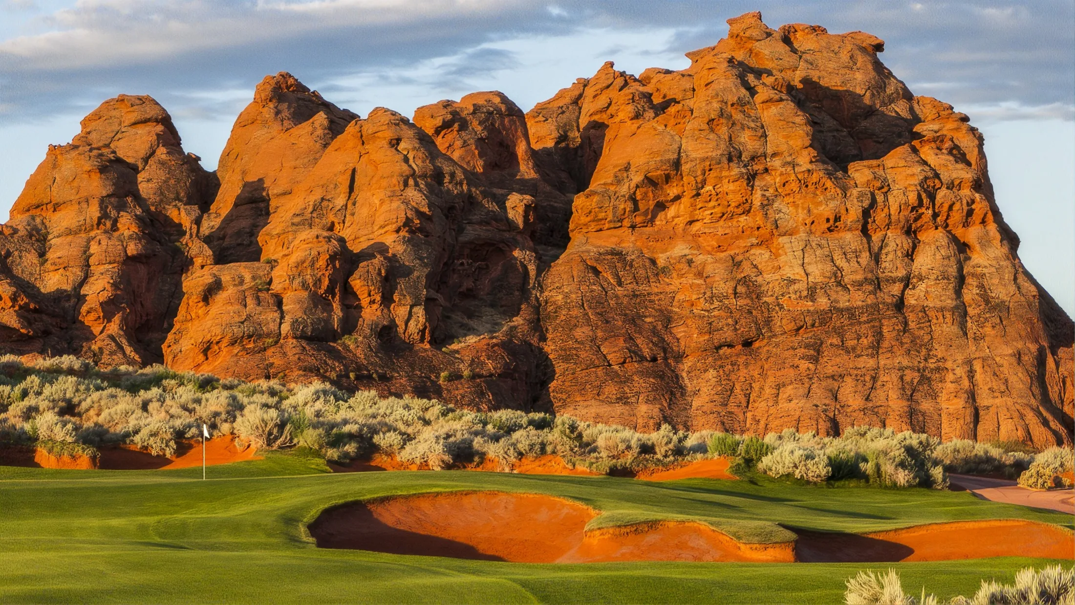 Golf course framed by red rock mountains